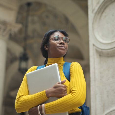 portrait of young woman with laptop in hands outside a school